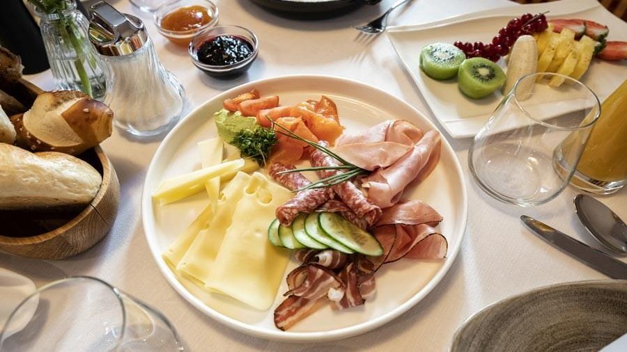 A beautifully arranged breakfast platter with meats, cheeses, and fresh fruits on a table.