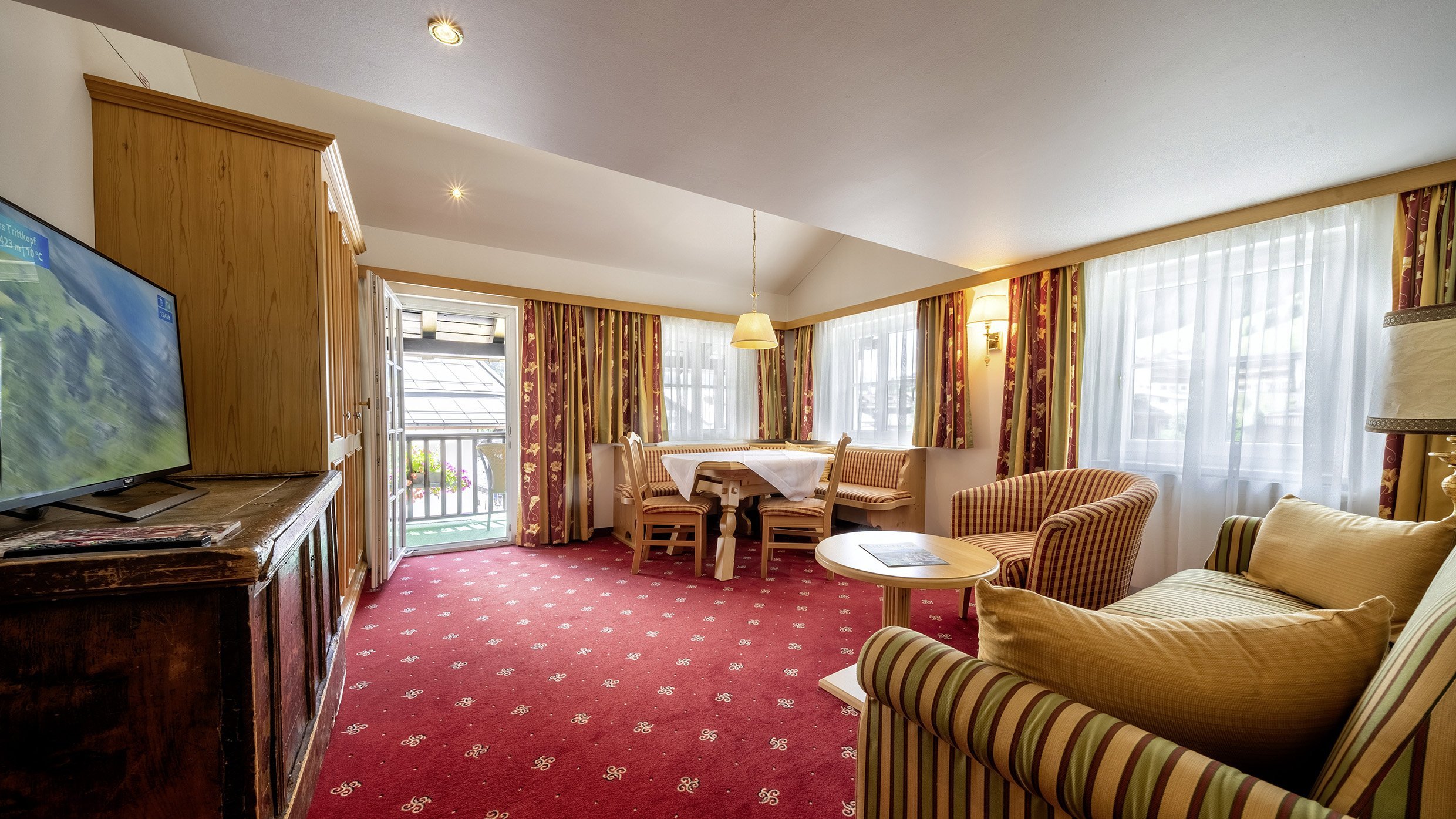 Hotelzimmer mit Wohnbereich, Essplatz und großen Fenstern für Tageslicht im Tannbergerhof