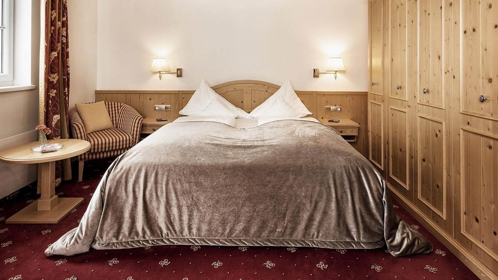 Doppelzimmer mit einem großen Bett, Holzschränken und einer Sitzecke für Entspannung