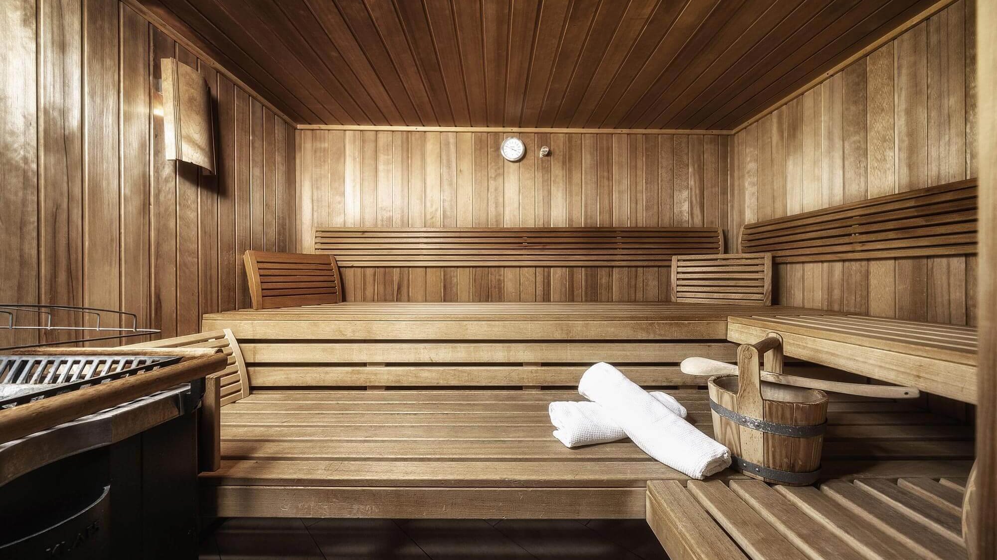 Die Holzsauna mit Bänken, Aufgusseimer, Handtüchern und Saunasteinofen im Tannbergerhof in Lech © Foto Lehmann