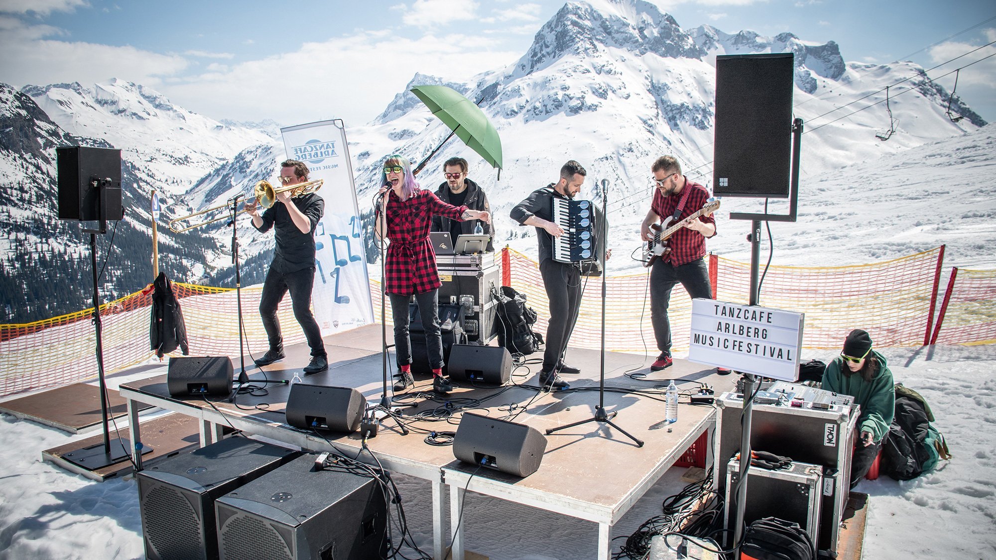 Band spielt auf einer Bühne in den verschneiten Bergen bei einem Festival im Freien.