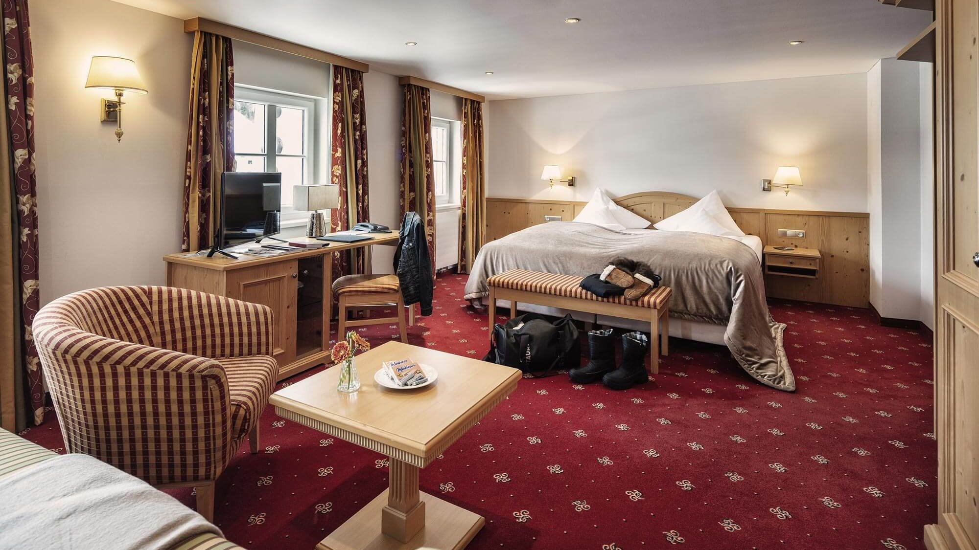 Hotelzimmer mit großem Bett, Schreibtisch und Sitzmöglichkeiten im Innenraum des Tannbergerhofs