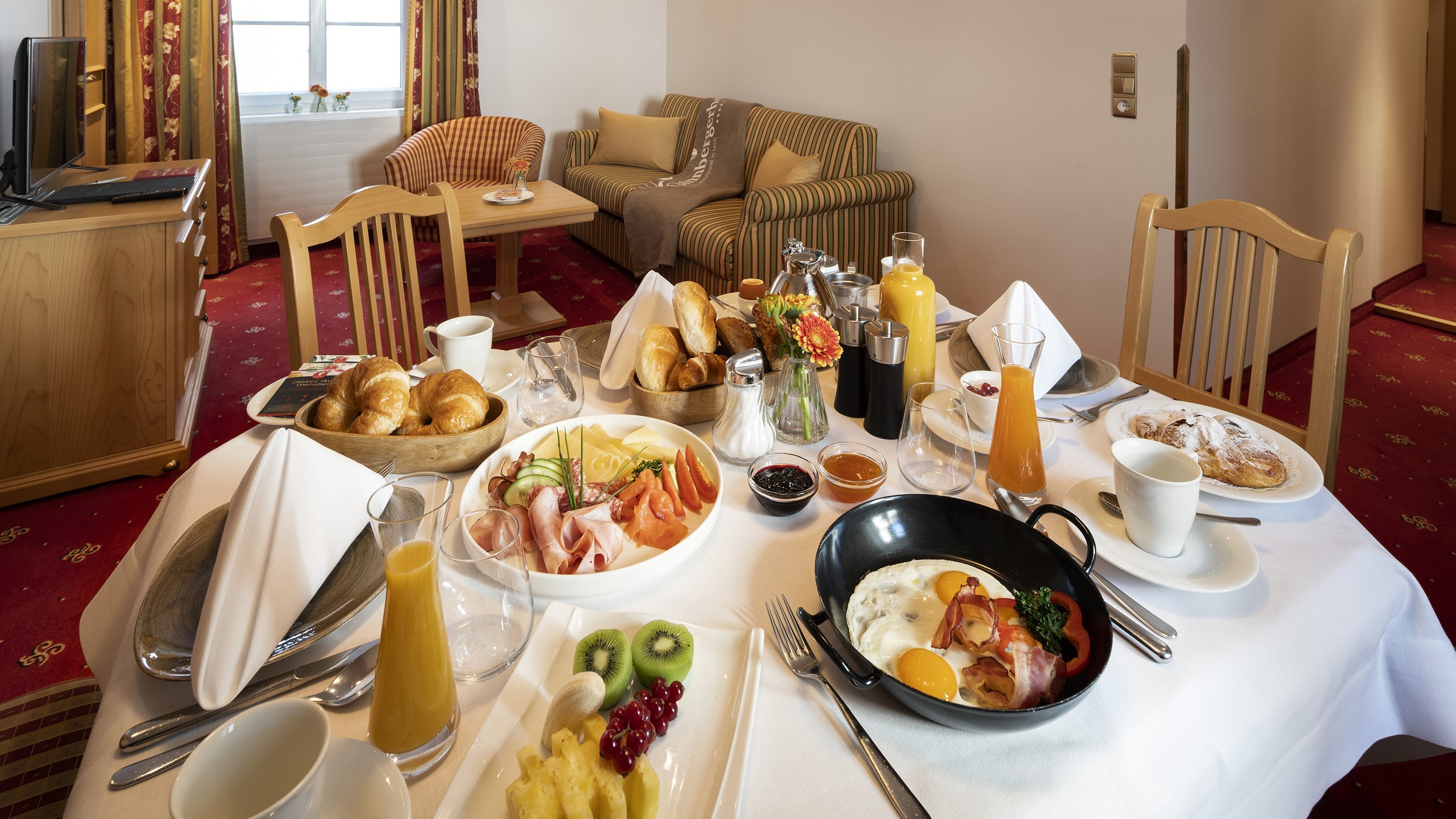 Ein gedeckter Tisch mit verschiedenen Speisen und Getränken im Hotelzimmer für das Frühstück.