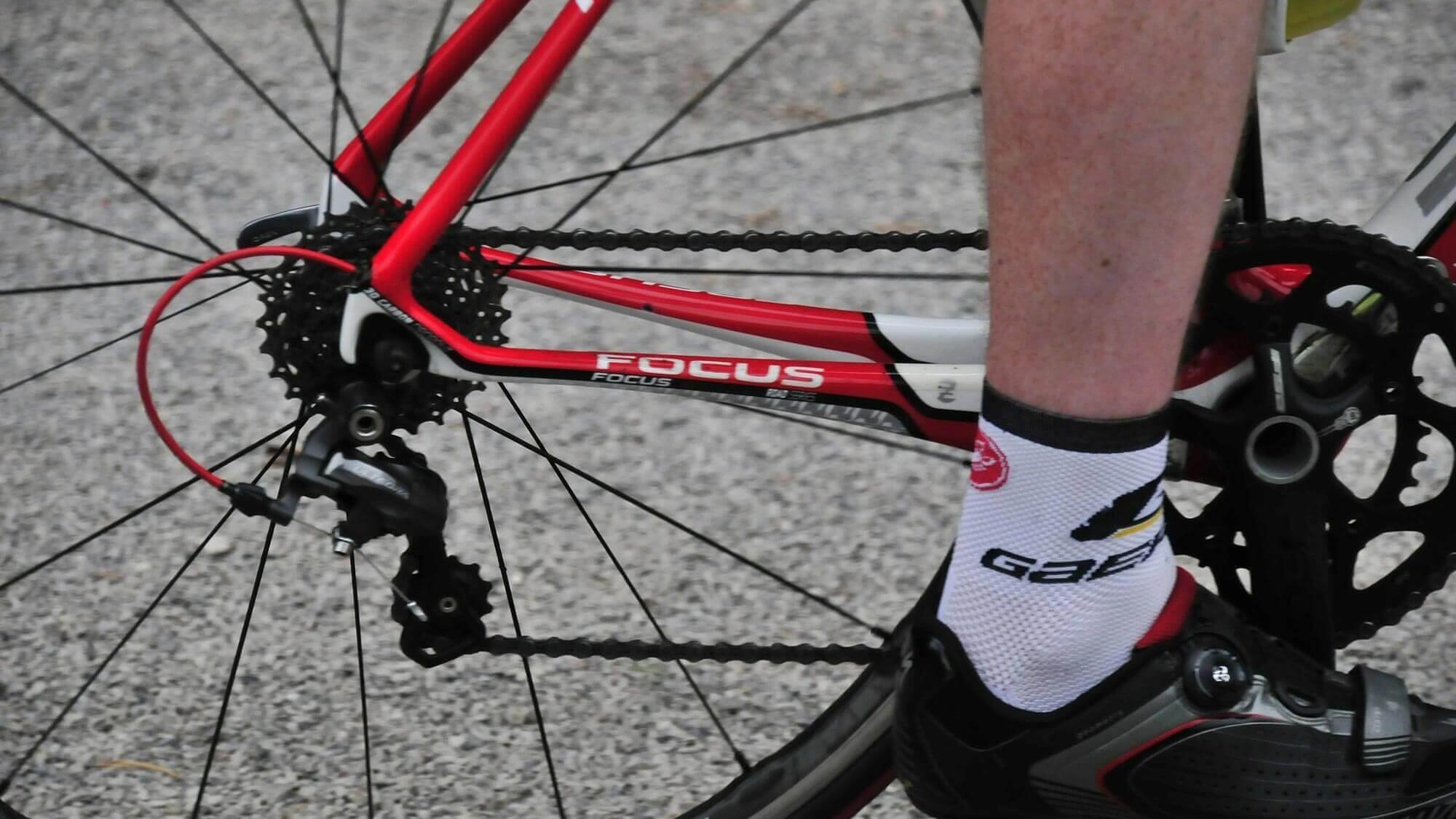 Nahaufnahme eines Radfahrers mit einem roten Rennrad und der Gangschaltung in Aktion.