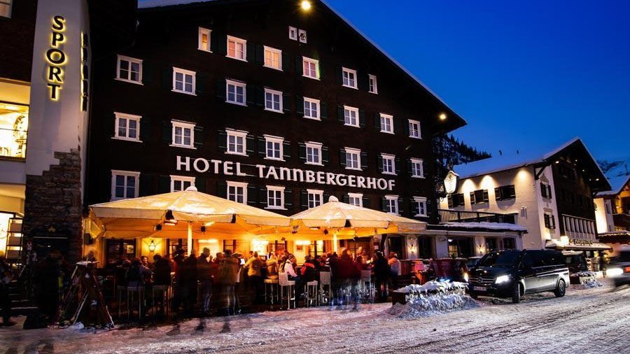 Outdoor dining areas at Hotel Tannbergerhof covered in snow during dusk with warm lights