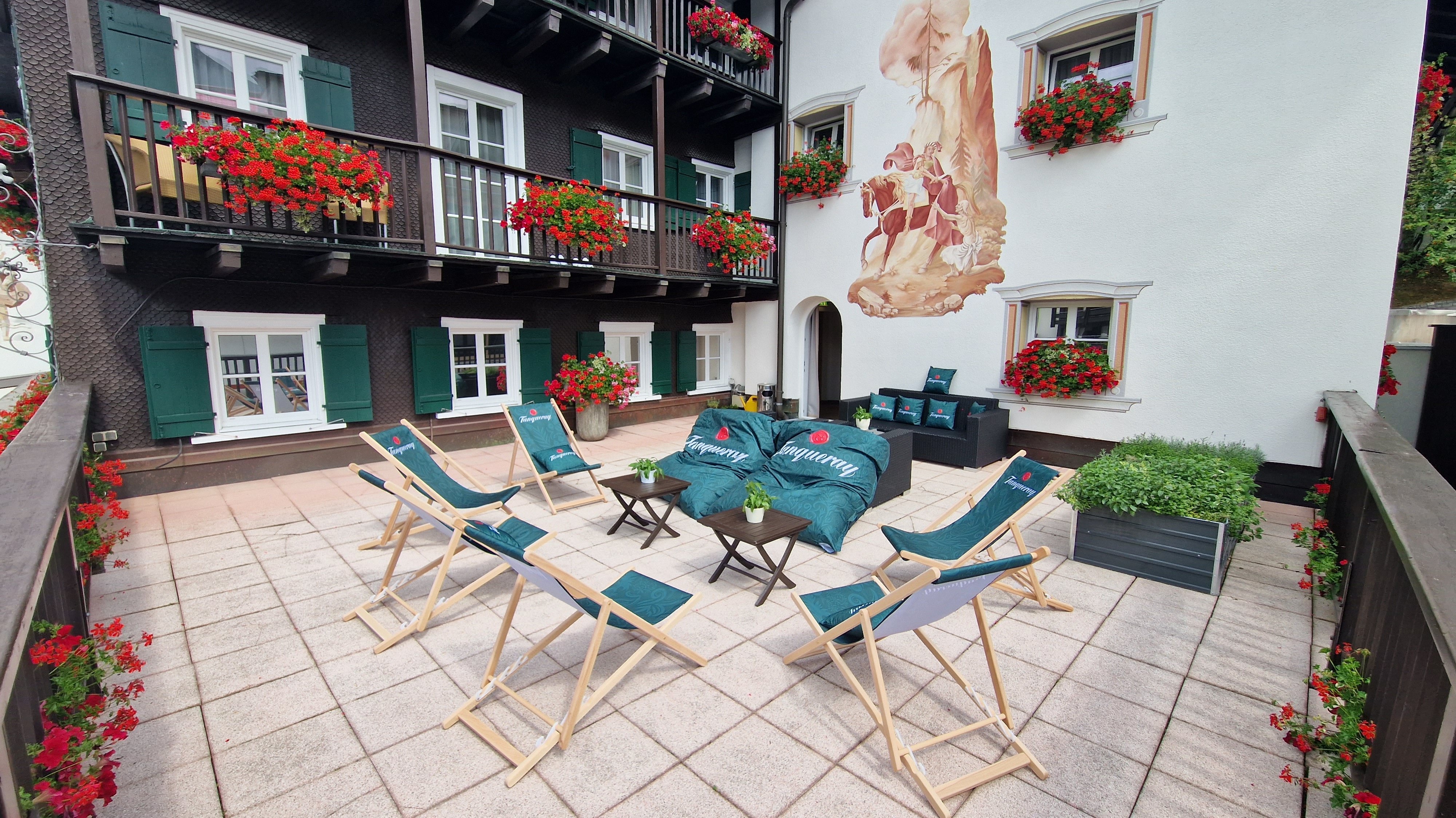 Gemütliche Sitzgelegenheiten auf der Hotelterrasse mit Blumenverzierungen und Wandmalerei