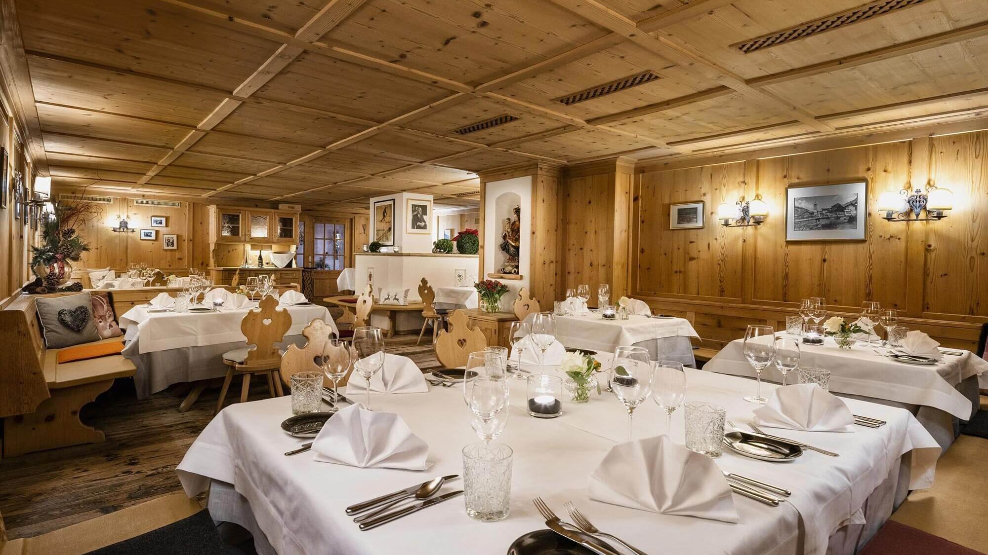 Gemütlicher Speisesaal mit Holzwänden und Tischgedecken für ein feines Dinnererlebnis