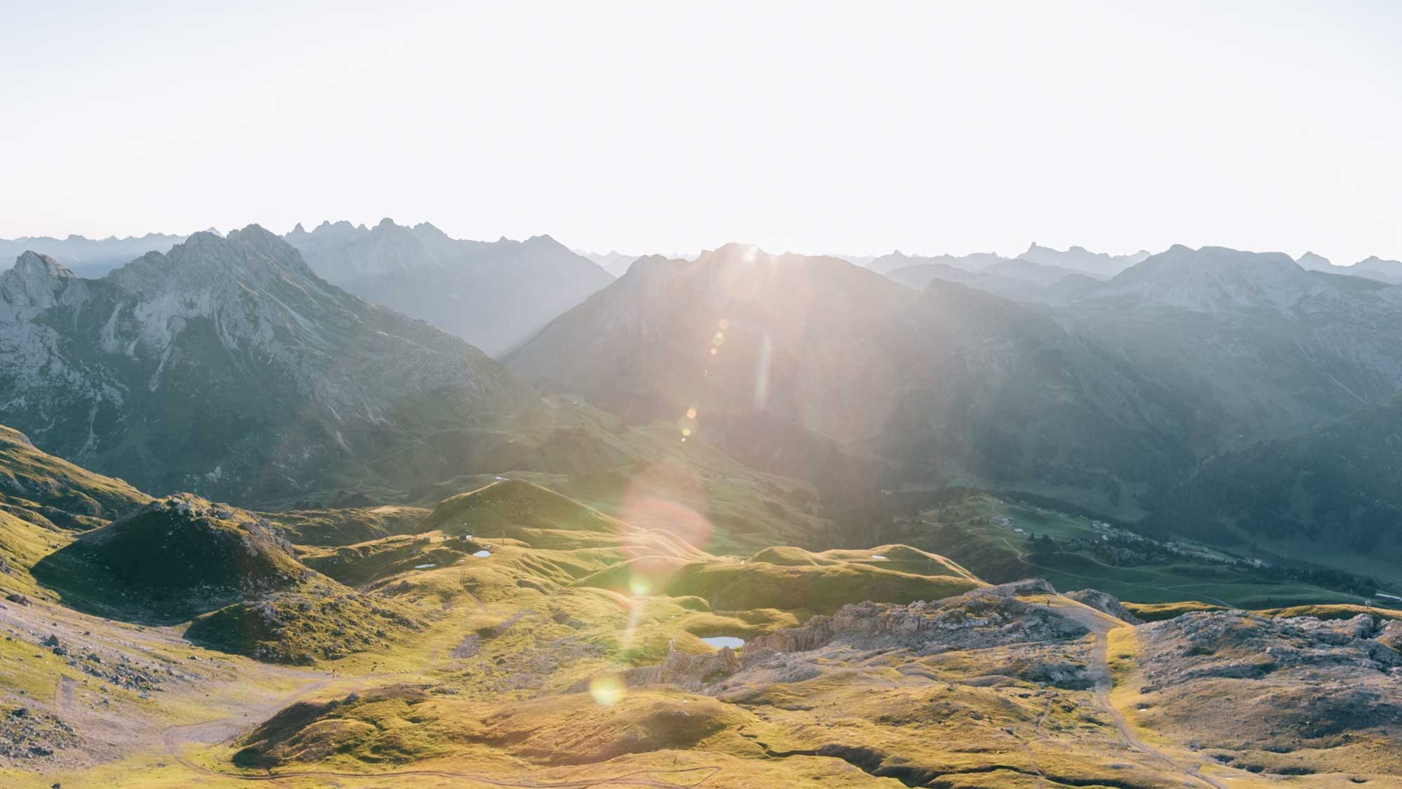 Panoramablick auf eine Berglandschaft mit Hügeln und Gipfeln während des Sonnenaufgangs