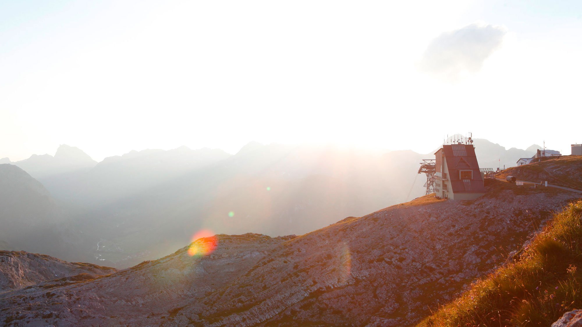Berglandschaft mit einer Hütte auf steinigem Gelände während des Sonnenuntergangs