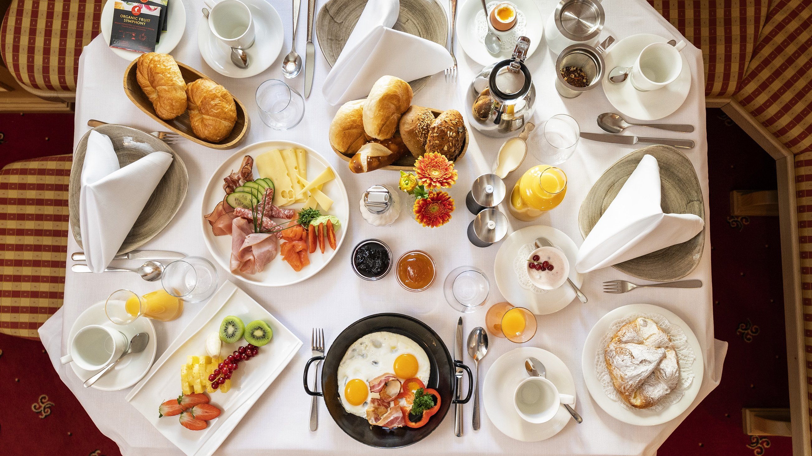 Ein liebevoll gedeckter Frühstückstisch mit Eiern, Fleisch, Obst und Gebäck für den Genuss am Morgen