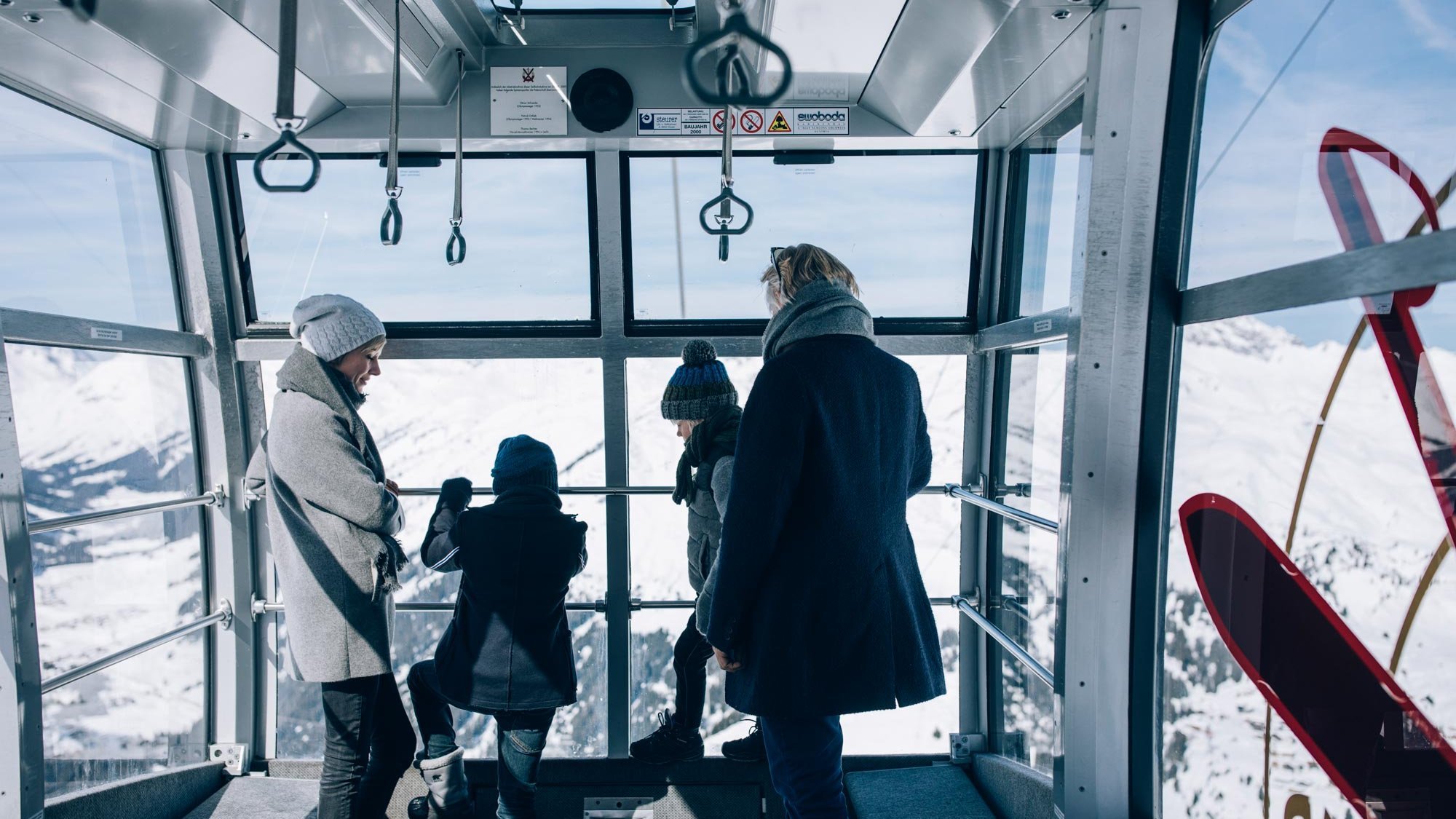 Gruppe von Personen in einer Gondel mit Blick auf verschneite Berge und eine Winterlandschaft