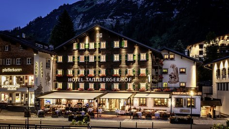 Nighttime Elegance at Tannbergerhof Hotel Tannbergerhof illuminated at night with mountains in the background, showcasing alpine architecture