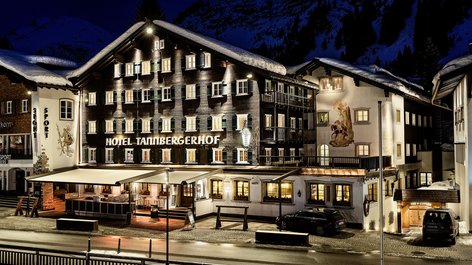 Illuminated Tannbergerhof hotel amidst snow-covered mountains at night, showcasing the beauty of the Alps