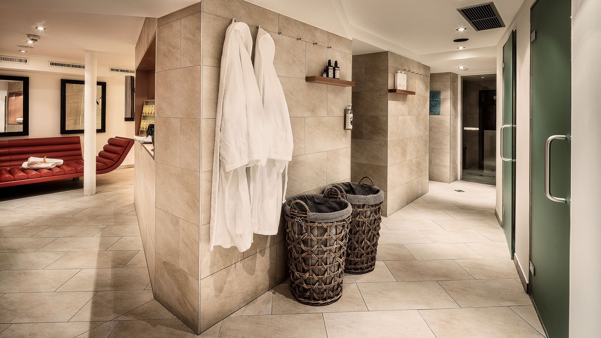 Entspannungsbereich mit roten Sitzmöbeln und gefalteten Bademänteln in einem modernen Spa