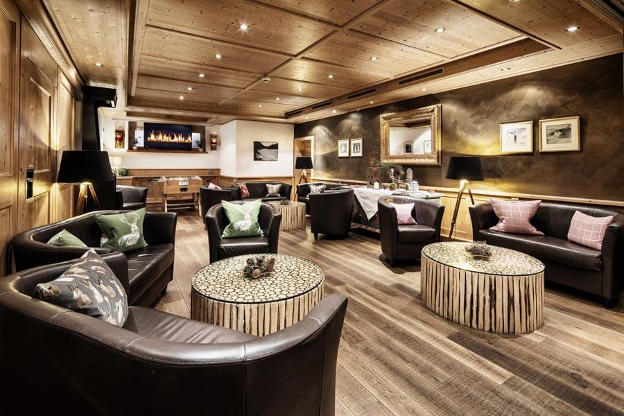 Gemütlicher Lounge-Bereich im Hotel Tannbergerhof in Lech mit Ledersesseln, Holztischen und Kaminfeuer © Foto Lehmann