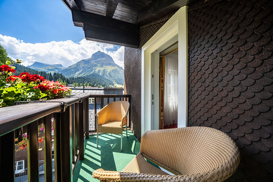 Balkon mit gemütlichen Sitzmöbeln und Blumen, mit Blick auf die beeindruckende Berglandschaft von Lech am Arlberg © Foto Lehmann