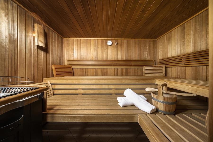 Die Holzsauna mit Bänken, Aufgusseimer, Handtüchern und Saunasteinofen im Tannbergerhof in Lech © Foto Lehmann